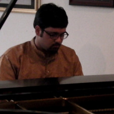 Photo of Pinaki playing a grand piano.